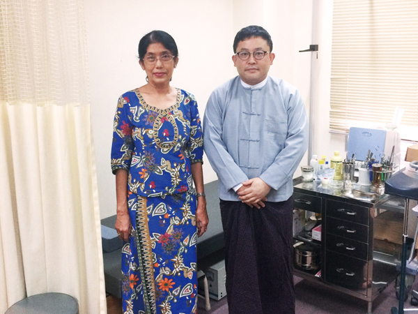 現地で業務をサポートしてくれるベテラン医務官秘書のDr. Nwe Nwe Aung氏と。診察室にてミャンマーの民族衣装を着て。　画像