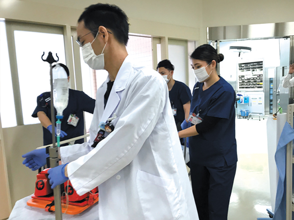 救急車で搬送された患者を受け入れ、救急初療室（ER）へと急ぐ竹村氏と救急スタッフ。　画像